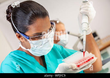 Weibliche Asiatische medizinische oder wissenschaftliche Forscher oder Arzt mit einer Pipette und Sample fach Blutprobe in einem Labor mit Frau Kollegin zu testen Stockfoto