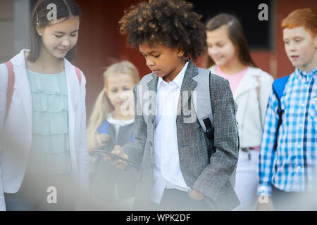 Afrikanische Schüler mit Rucksack stehen und Tippen auf Handy mit Schülerin, die bei ihm standen draußen er Ihre Telefonnummer gespeichert Stockfoto