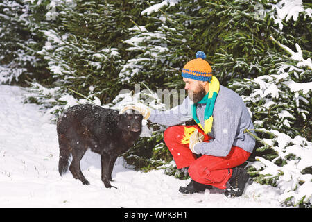 Mann mit Hund Winter mit Schnee im Wald. Freundschaft mit Hunden. Stockfoto