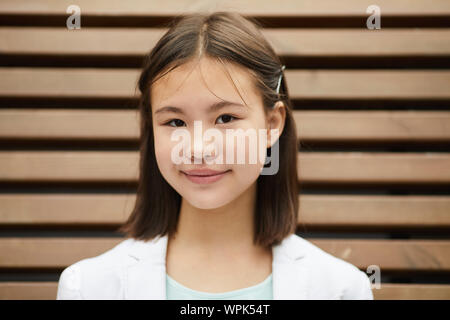 Portrait von Asiatische Schulmädchen mit kurzen braunen Haaren auf Kamera beim Stehen im Freien Stockfoto