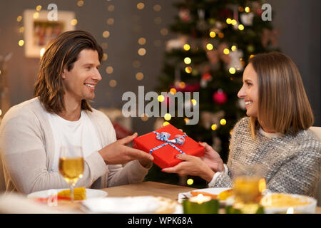 Schönes Paar teilen präsentiert während Weihnachten Abendessen Stockfoto