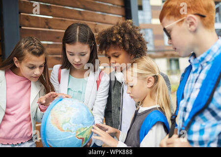 Gruppe von multiethnischen Schule Kinder im Globe zeigen Sie lernen die Geographie des Landes Stockfoto