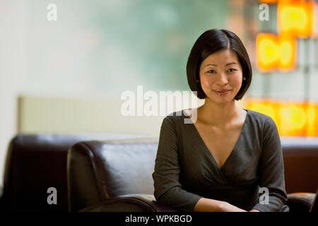 Frau sitzt auf einem Sofa in der Lobby. Stockfoto