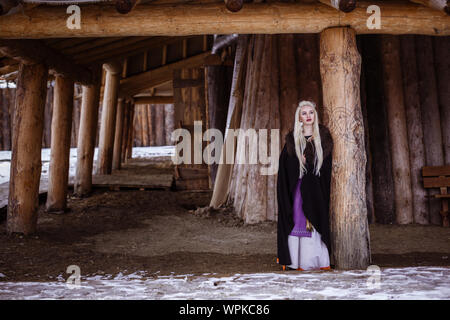 Im freien Porträt der Schönen wütend skandinavischen Krieger Ingwer Frau in traditioneller Kleidung mit Pelzkragen, mit Schwert in der Hand und Holz- V Stockfoto