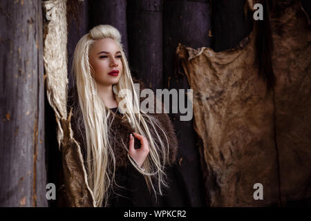 Im freien Porträt der Schönen wütend skandinavischen Krieger Ingwer Frau in traditioneller Kleidung mit Pelzkragen, mit Schwert in der Hand und Holz- V Stockfoto