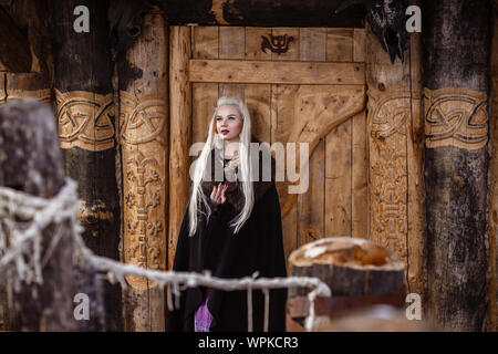 Im freien Porträt der Schönen wütend skandinavischen Krieger Ingwer Frau in traditioneller Kleidung mit Pelzkragen, mit Schwert in der Hand und Holz- V Stockfoto