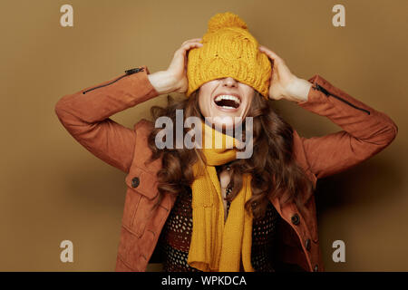Hallo Herbst. Freundliche elegante Frau in gelber Schal mit Baskenmütze über Augen auf beigem Hintergrund. Stockfoto