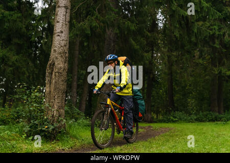 Ausgestattete männlichen bikepacker Fahrten entlang einer Spur in einem Fichtenwald Stockfoto