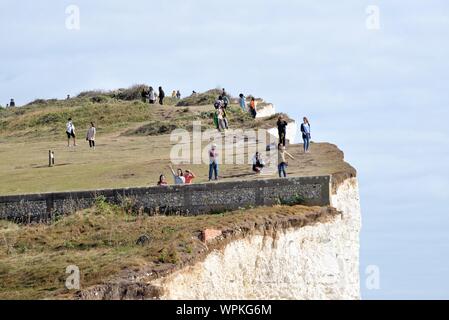 Junge koreanische Touristen fotografieren stehen am Rand der Kreidefelsen am Birling Gap Eastbourne East Sussex England Großbritannien Stockfoto