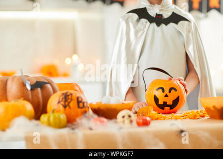 Nahaufnahme der Junge im Kostüm steht in der Nähe des Tisches mit Kürbissen und Laternen an Halloween Party gekleidet Stockfoto