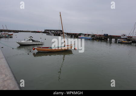 Blick auf die Boote in Bridlington Hafen mit erweiterter Tiefenschärfe. Ein Yorkshire coble Sand ein kleines Boot mit Reflexionen sind im Mittelpunkt. Stockfoto