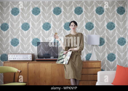 Junge Frau Mitte centuryfashion mit LP und Champagner posing Stockfoto