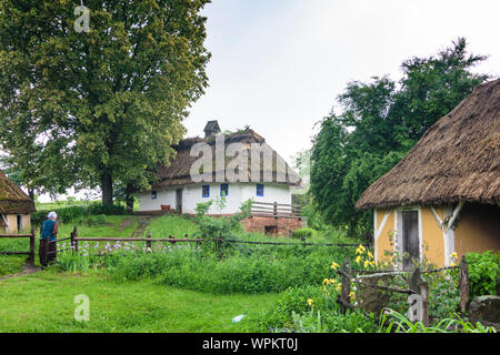 Kiew, Kiew: Museum der Volksarchitektur und Folkways in der Ukraine Pyrohiv, Holzhaus, Reetdach, Museum Hausmeister in traditioneller Kleidung, Stockfoto