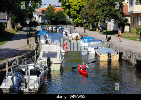 Trosa, Schweden - 28. August 2019: Zwei rote Meer Kajaks in der trosa Fluss mit angelegten Sportboote. Stockfoto