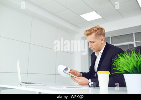 Ernsthafte Geschäftsmann denkt an einem Tisch an einem Arbeitsplatz in einem Büro. Stockfoto
