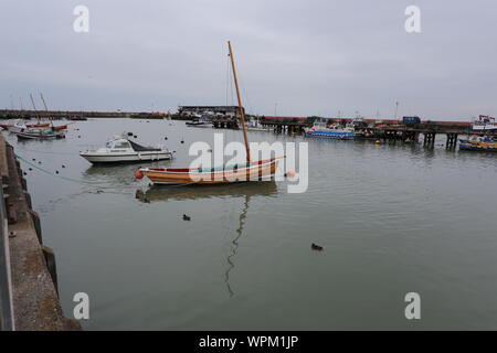 Boote mit Reflexionen in Bridlington Hafen. Im Vordergrund ist ein typischer Yorkshire Coble. Stockfoto