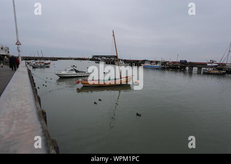 Boote mit Reflexionen in Bridlington Hafen. Im Vordergrund ist ein typischer Yorkshire Coble. Stockfoto