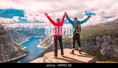 Paar posiert auf Trolltunga. Froh, dass Frau und Mann schönen See und gutes Wetter in Norwegen genießen. Stockfoto