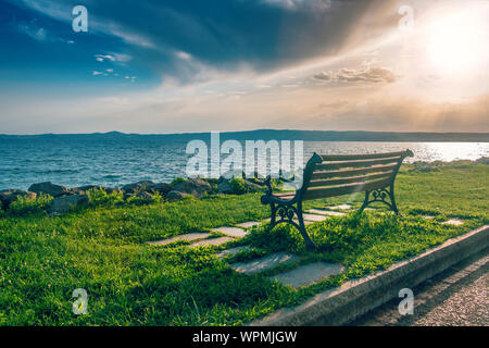 Einsamen alten Holzbank am Meer bei Sonnenuntergang, Konzept Foto Stockfoto