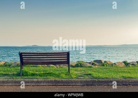 Einsamen alten Holzbank am Meer bei Sonnenuntergang, Konzept Foto Stockfoto