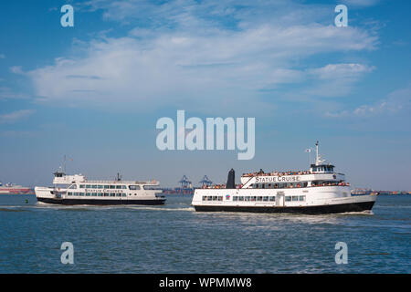 Liberty Cruise New York City, Blick auf vorbeifahrende Kreuzfahrtboote, die zwischen der Freiheitsstatue und dem Battery Park Ferry Terminal, New York City, USA, fahren Stockfoto