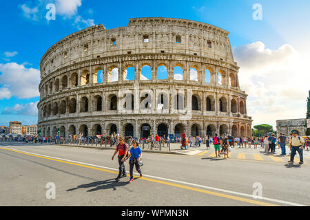 Die antike Arena, das Kolosseum von Rom in Italien an einem Sommertag mit Touristen, die über die Via dei Fori Imperiali Stockfoto