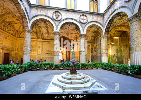 Touristen besuchen die ersten Innenhof des Palazzo Vecchio in Florenz Italien mit einem kleinen Brunnen mit Statue, Fresken an der Wand und gewölbten Spalte Stockfoto