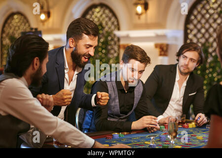 Ein junger Mann ist glücklich, im Casino zu gewinnen. Stockfoto