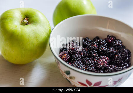 Eine Schale mit frisch gepflückten Brombeeren und kochen Äpfel. Stockfoto