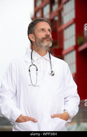 Portrait von gut aussehenden bärtigen Arzt im weißen Kittel vor Stockfoto