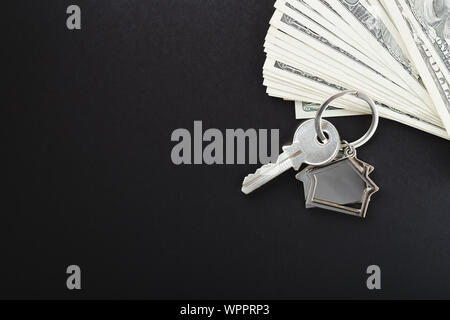 Haus Schlüssel über das hundert Dollar Banknoten auf schwarzem Hintergrund. Stockfoto