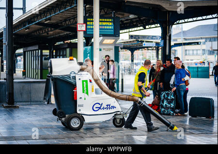 Ostende, Belgien - May 16, 2011: Arbeiter mit elektrische Vakuum Maschine Vielfraß auf Reisende, die sich ein Gruppenfoto in Ostende Centraal Station Stockfoto