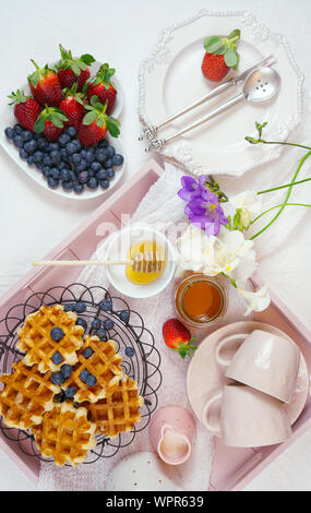 Moderne Blush Pink Frühstück mit Waffeln, Honig und Obst. Stockfoto