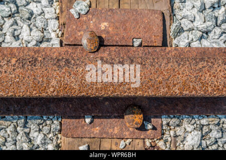 Eine befreit railroad Track mit Spike und Platte statt nach unten auf einen Riegel Holz verrostet und an einem sonnigen Tag schließen Stockfoto