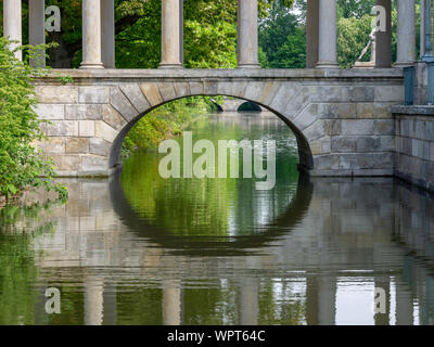 Eine neoklassizistische Brücke mit Säulen im Wasser widerspiegelt. Architektur aus dem 19. Jahrhundert. Park, Frühling, sonnigen Tag. Stockfoto