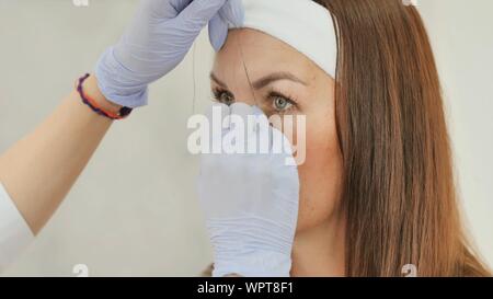 Das Mädchen Kosmetikerin Marken mit Hilfe von Gewinde Augenbraue tattoo. Permanent Make-up. Dauerhafte Tätowierung der Augenbrauen. Stockfoto