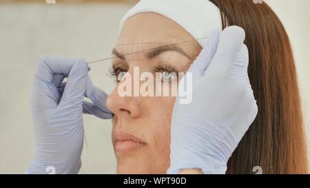 Das Mädchen Kosmetikerin Marken mit Hilfe von Gewinde Augenbraue tattoo. Permanent Make-up. Dauerhafte Tätowierung der Augenbrauen. Stockfoto