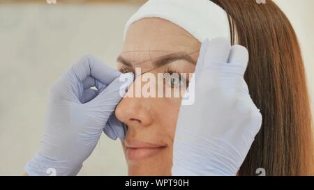 Das Mädchen Kosmetikerin Marken mit Hilfe von Gewinde Augenbraue tattoo. Permanent Make-up. Dauerhafte Tätowierung der Augenbrauen. Stockfoto