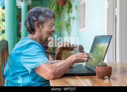 Lächelnde ältere Frau mit Brille mit einem Laptop Stockfoto