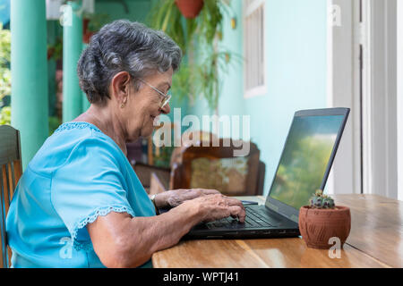 Lächelnde ältere Frau mit Brille mit einem Laptop Stockfoto