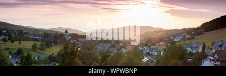 Weiten Panoramablick über die bergige Dorf von Grafschaft im Winter Sport Region Sauerland, Deutschland, während ein farbenfroher Sonnenuntergang Stockfoto