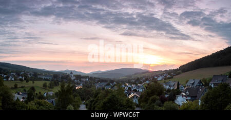 Weiten Panoramablick über die bergige Spa Village von Grafschaft im Winter Sport Region Sauerland, Deutschland, bei Sonnenuntergang Stockfoto