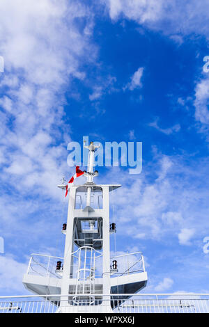 Weiße Schiff Navigation und Kommunikation Turm Mast, hintere Ansicht von unten mit der kanadischen Flagge gegen bewölkt blauer Himmel. Stockfoto