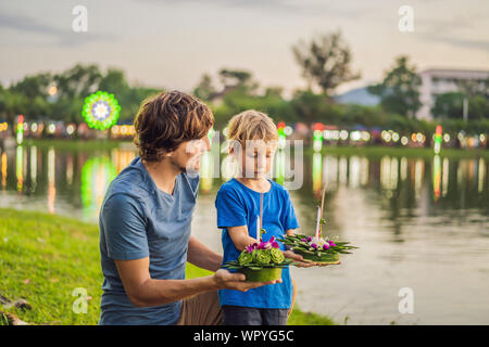 Vater und Sohn Touristen hält die Loy Krathong in ihren Händen und es geht um in das Wasser zu starten. Loy Krathong Festival, die Menschen kaufen Blumen und Stockfoto