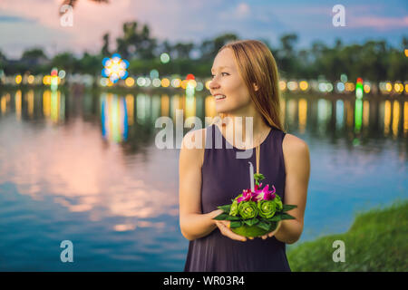 Eine weibliche Touristen hält die Loy Krathong in ihren Händen und es geht um in das Wasser zu starten. Loy Krathong Festival, die Menschen kaufen Blumen und Kerzen Stockfoto