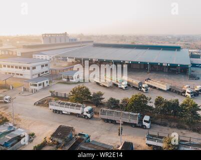 Luftaufnahme der in der Nähe des Lagerhauses geparkten Werksfahrzeuge Tagsüber Stockfoto