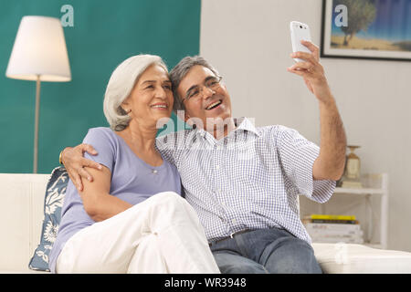 Seniorenpaar, das sich mit einem Mobiltelefon fotografiert Stockfoto