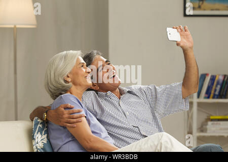 Seniorenpaar, das sich mit einem Mobiltelefon fotografiert Stockfoto