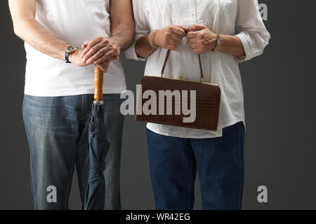 Mittelteil Blick auf einen alten Mann mit Regenschirm und seine Frau hält eine Handtasche Stockfoto