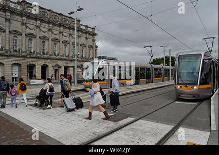 Fahrgäste Kreuz vor der LUAS-Straßenbahn am Bahnhof Heuston, Dublin, Irland Stockfoto